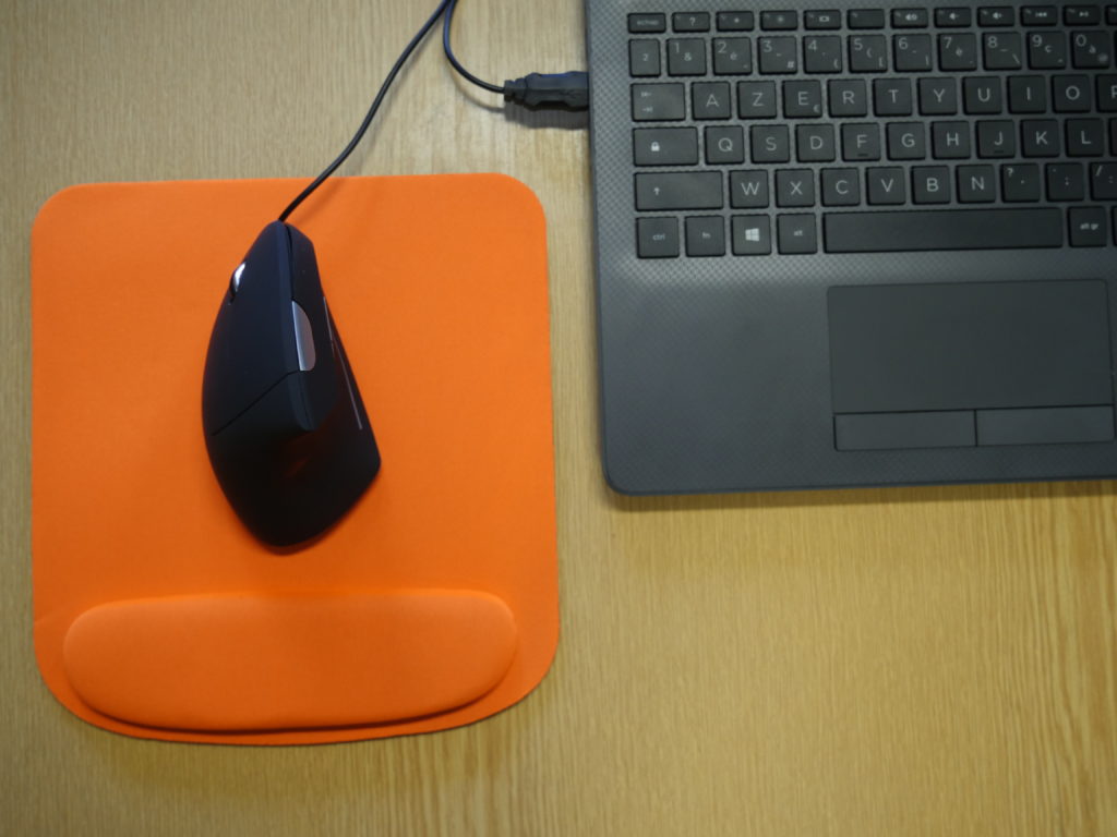 Photo d'une souris verticale noire sur un tapis de souris orange.